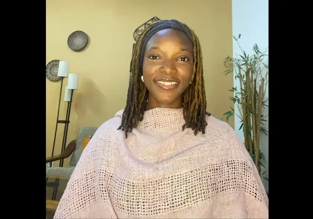 A young African woman in a pink shawl smiles